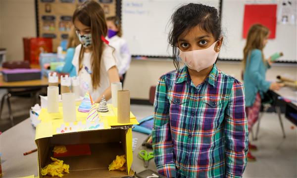Student holds up a castle made out of recycled materials